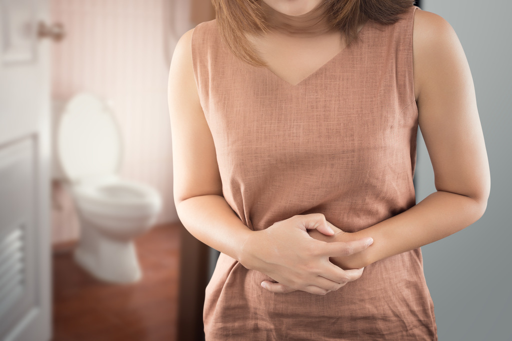 A Man Sitting on a Couch Holding His Stomach With an Illustration of Internal Digestive Organs Symptoms of Digestive Issues